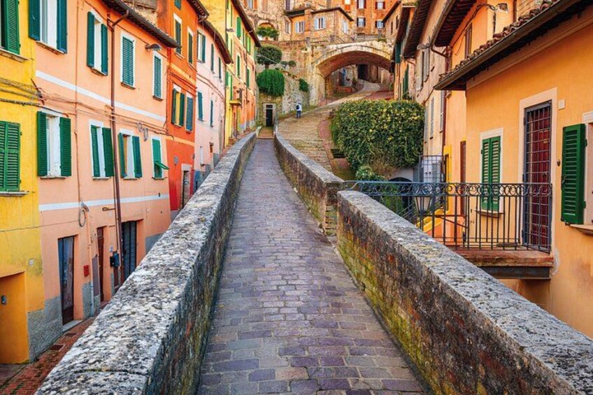 A narrow cobblestone street flanked by colorful buildings with green shutters. 3