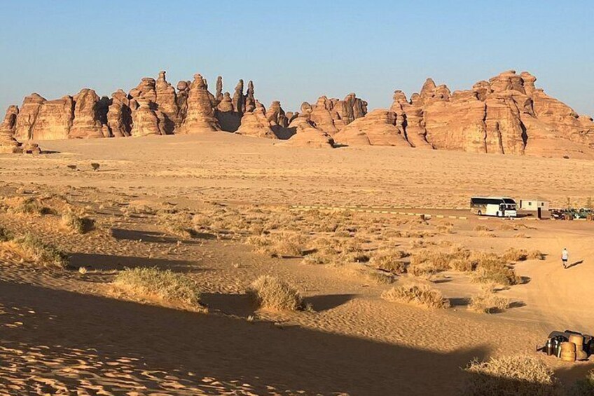 A desert landscape with rock formations, a dirt road, and a vehicle. 4
