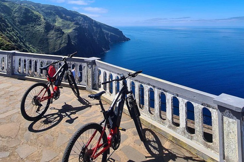 Two bicycles parked on a stone platform overlooking a coastal landscape. 4