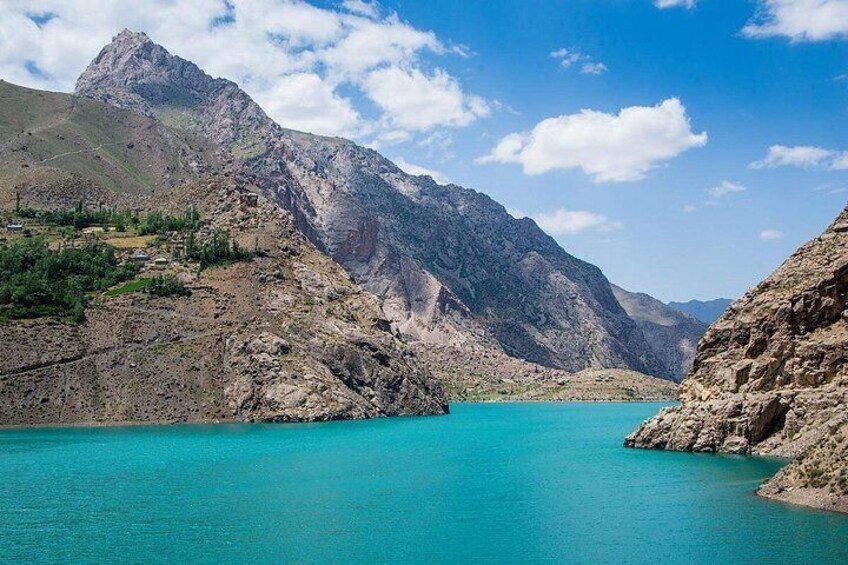 Ein türkisfarbenes See, umgeben von zerklüfteten Bergen, mit blauem Himmel darüber. 4