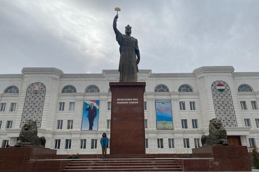 Una estatua de un hombre sosteniendo una antorcha, un edificio con columnas, y un cartel con un retrato. 2