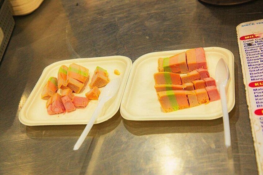 Two plastic containers with food items and a spoon, placed on a metallic surface. 2