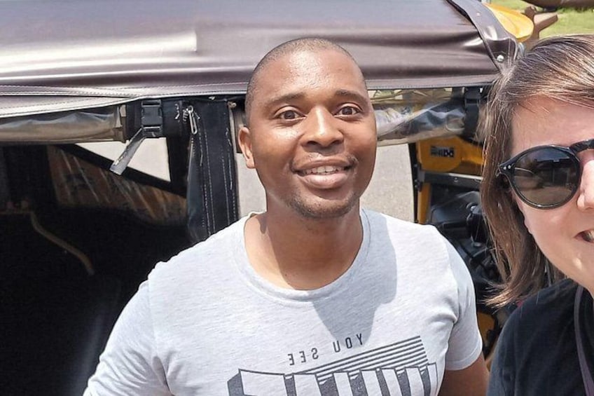 A person wearing a white t-shirt with a graphic design, standing outdoors with a vehicle in the background. 2