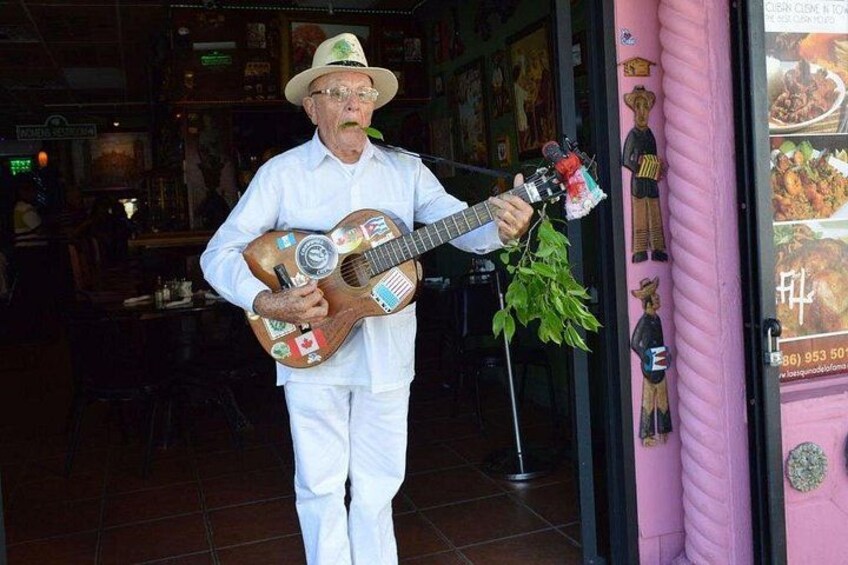 Een man met een witte shirt en hoed speelt gitaar. 2