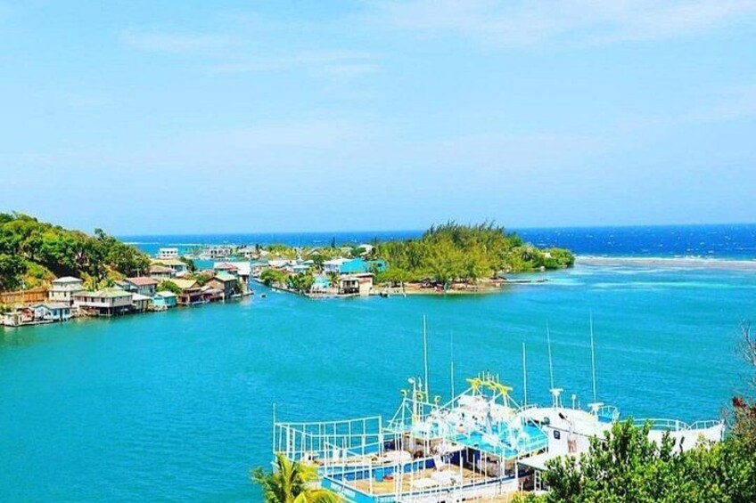 A coastal town with houses, a marina, and a clear blue sea. 4