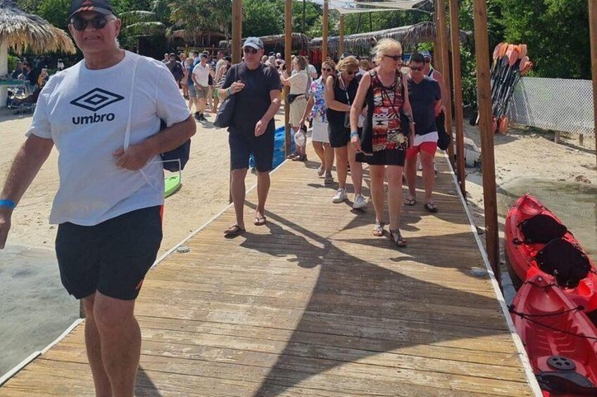 A wooden boardwalk with people walking, a red kayak, and a beach setting. 2