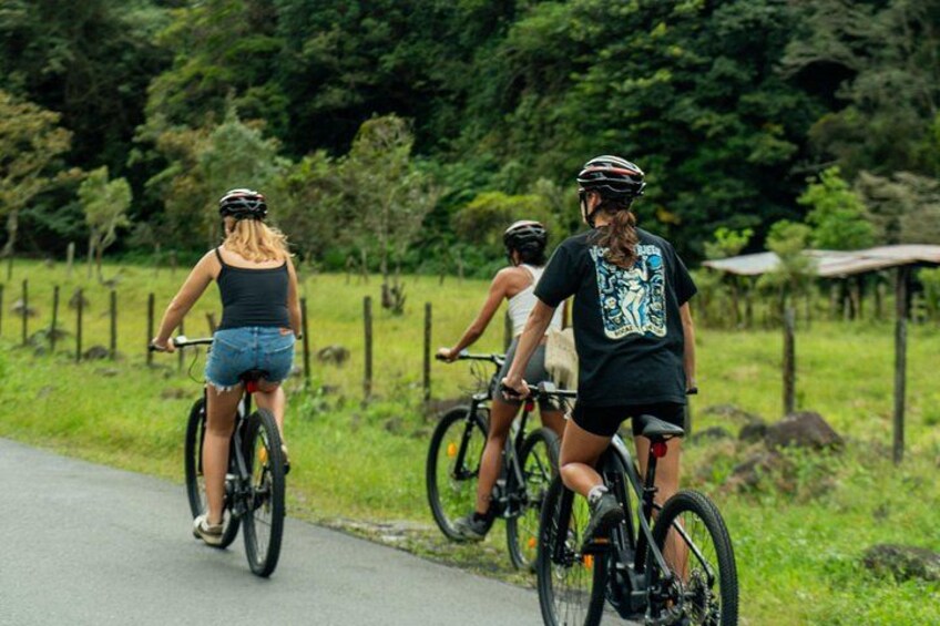 Three cyclists on a paved path surrounded by greenery. 2