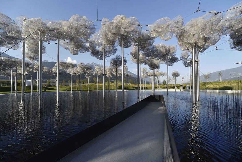 A reflective water feature with transparent, bubble-like structures resembling trees, set against a mountainous backdrop. 2