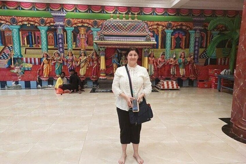 A person standing in front of a colorful temple interior with intricate artwork and statues. 3