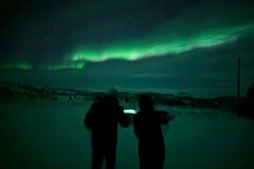 Deux personnes observant les aurores boréales dans un paysage enneigé. 1