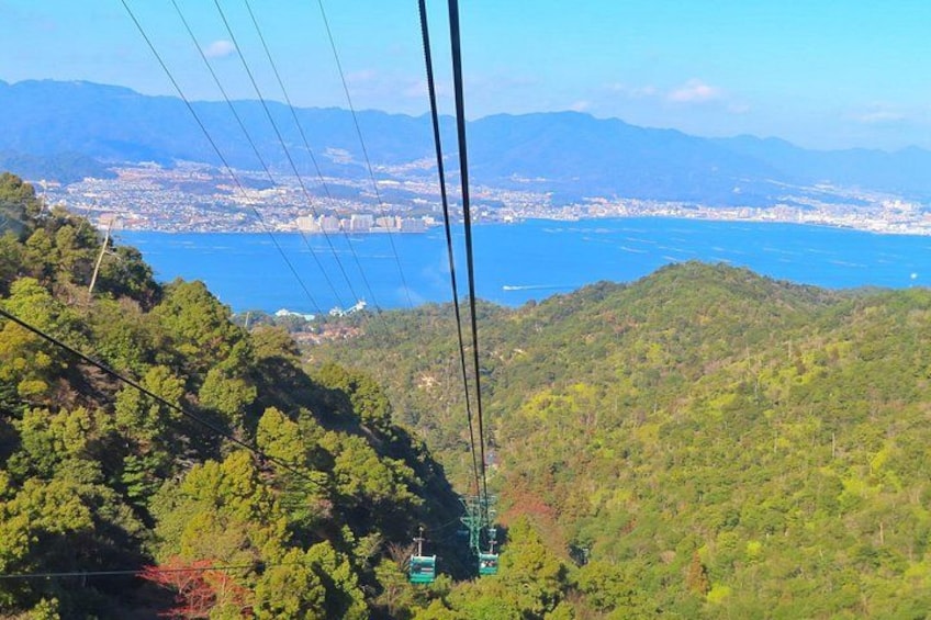A cable car system, lush green hills, and a distant cityscape with a body of water. 1