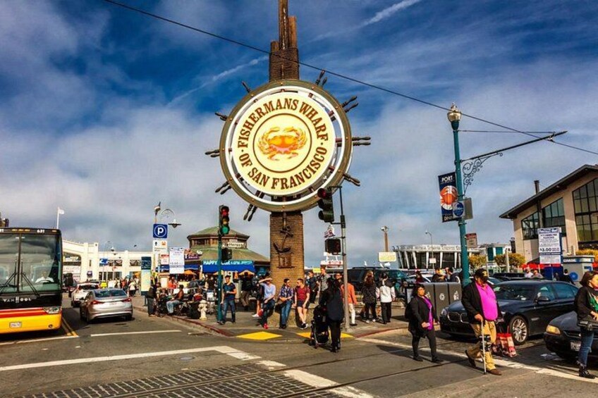 A busy street with a large circular sign reading 'Fisherman's Wharf San Francisco.' 3