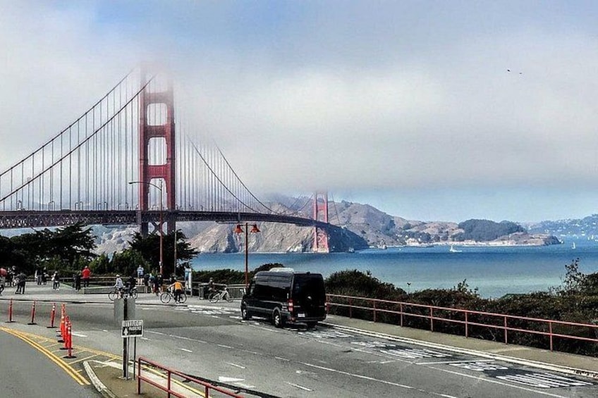 The Golden Gate Bridge, a suspension bridge, with a vehicle on the road, and a clear view of the surrounding landscape. 5