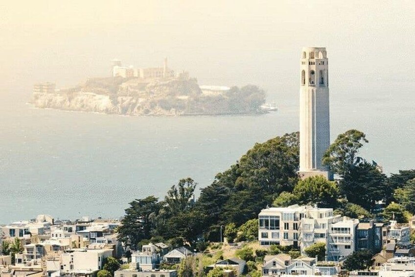 A coastal cityscape with a prominent white tower, dense greenery, and a distant island with buildings. 4