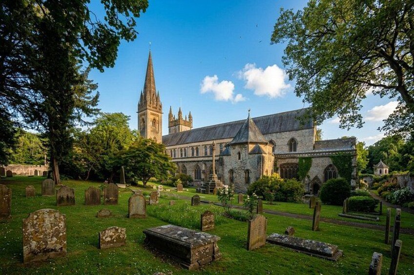 A historic church with a tall spire, surrounded by a cemetery with headstones. 2
