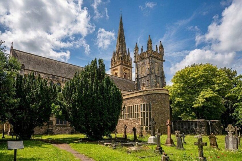 A historic church with a tall spire, a stone building, and a cemetery with gravestones. 3