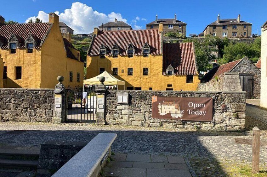 A historic building with a yellow facade, a stone wall, and a sign that reads 'Open Today.' 3