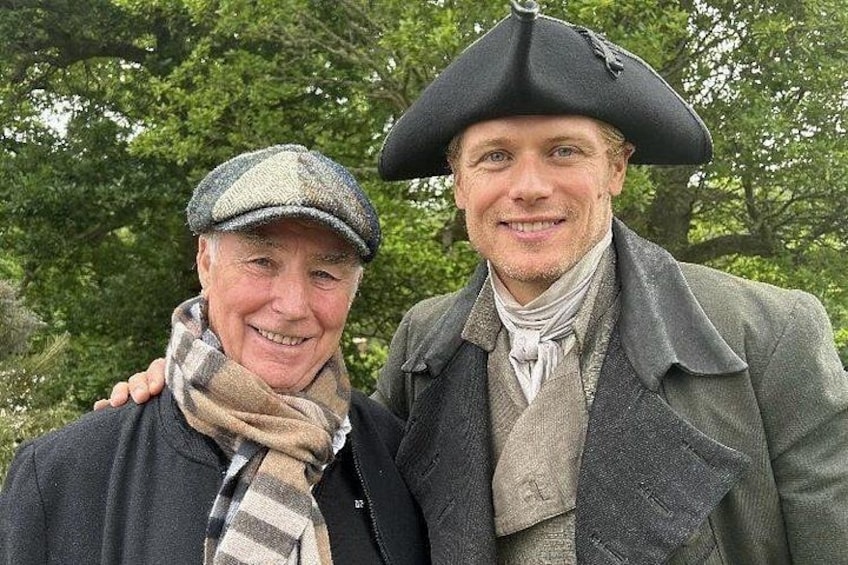 Two people in historical costumes with trees in the background. 1