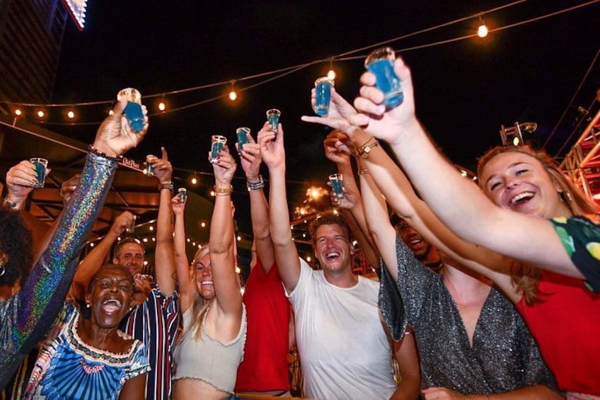 A group of people holding up drinks at an outdoor event. 2