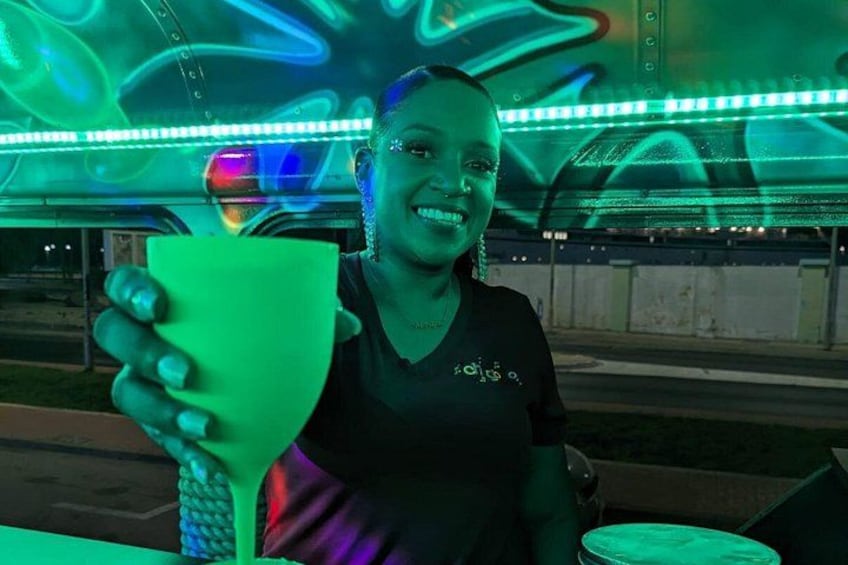 A person holding a green object in an outdoor setting with colorful lights in the background. 3