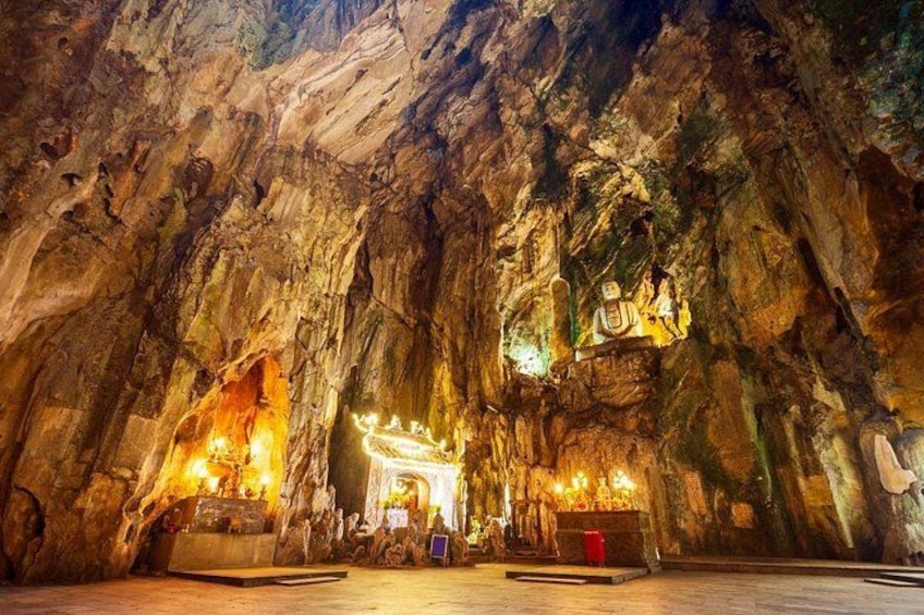 Une grotte ornée de statues illuminées et abritant un sanctuaire central. 1