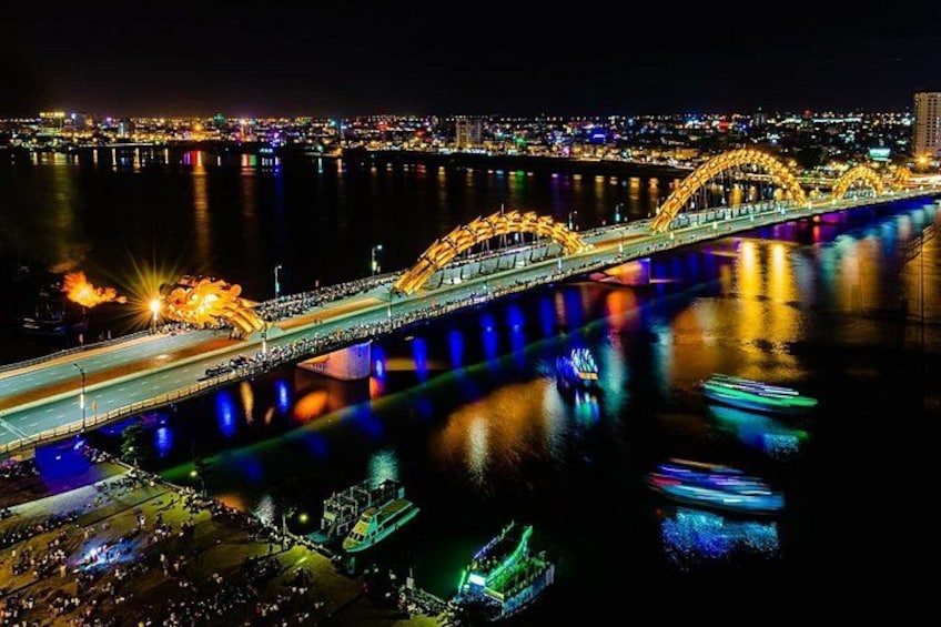 Un pont illuminé de mille feux, dont les lumières se reflètent sur l’eau, une route très fréquentée et, au loin, une vue sur la ville. 5