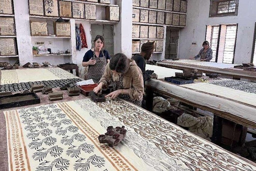 Een workshop met mensen die bezig zijn met textielwerk, met opvallende stoffen en gereedschappen. 5