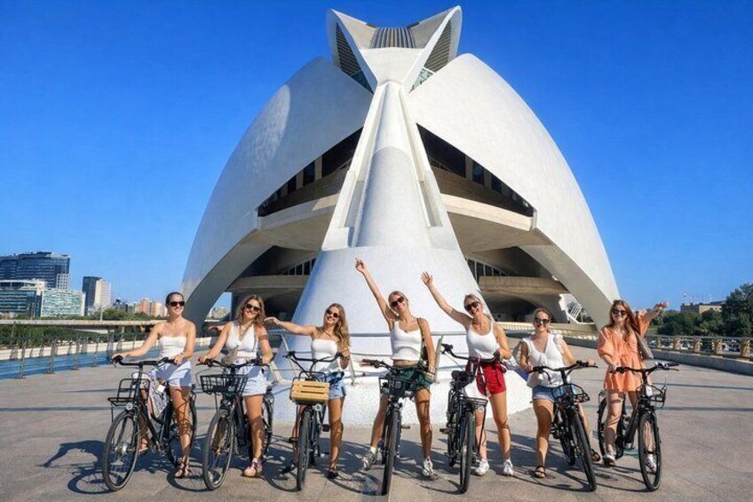 Un gruppo di persone in bicicletta di fronte a una moderna costruzione architettonica. 1