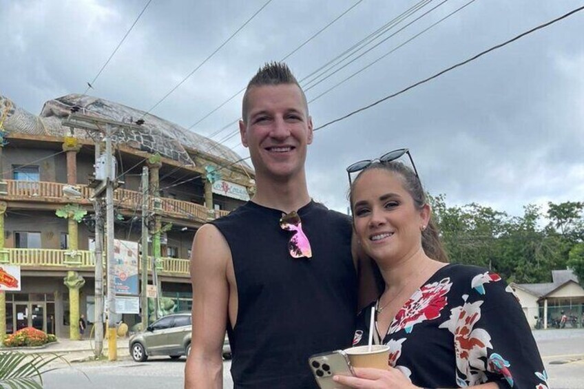 A person in a black sleeveless shirt and another in a floral top holding a drink. 2