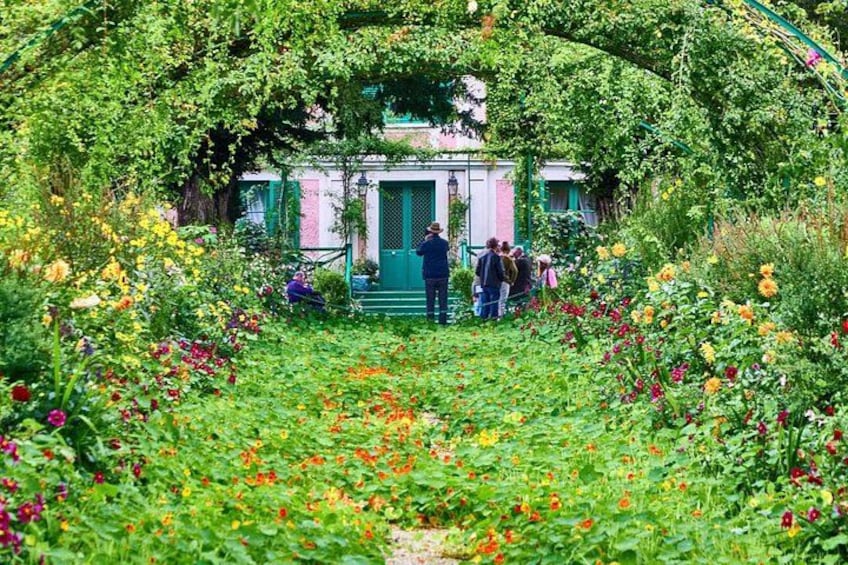 A garden with a gazebo, people, and colorful flowers. 5