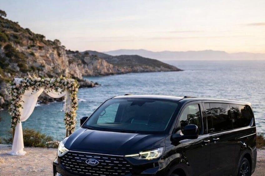 A black Ford SUV parked by a coastal area with a floral archway and rocky cliffs in the background. 1