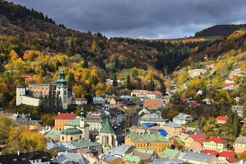 A town with a prominent church, colorful autumn foliage, and a castle-like building. 1