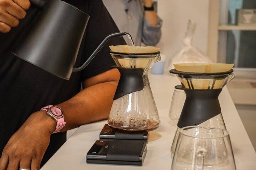 A person pouring liquid from a black mug into a coffee maker. 5