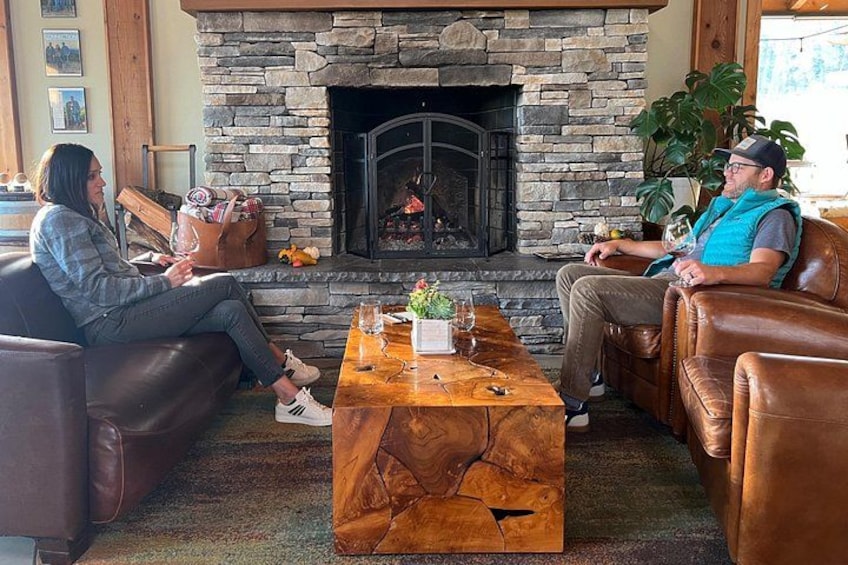 Two people sitting on leather couches facing each other in a room with a stone fireplace. 4