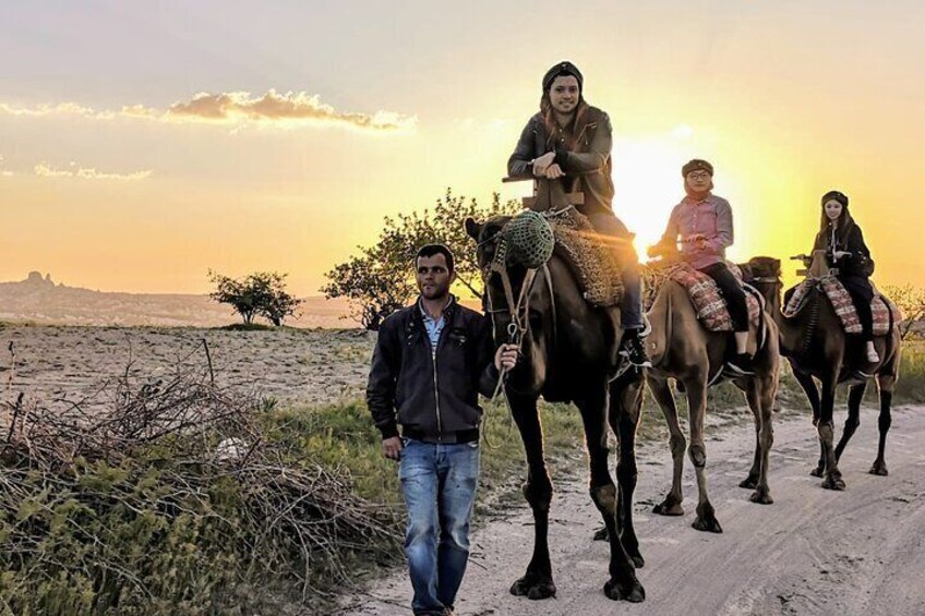 Tres personas montando a caballo por un sendero de tierra con el atardecer de fondo. 1