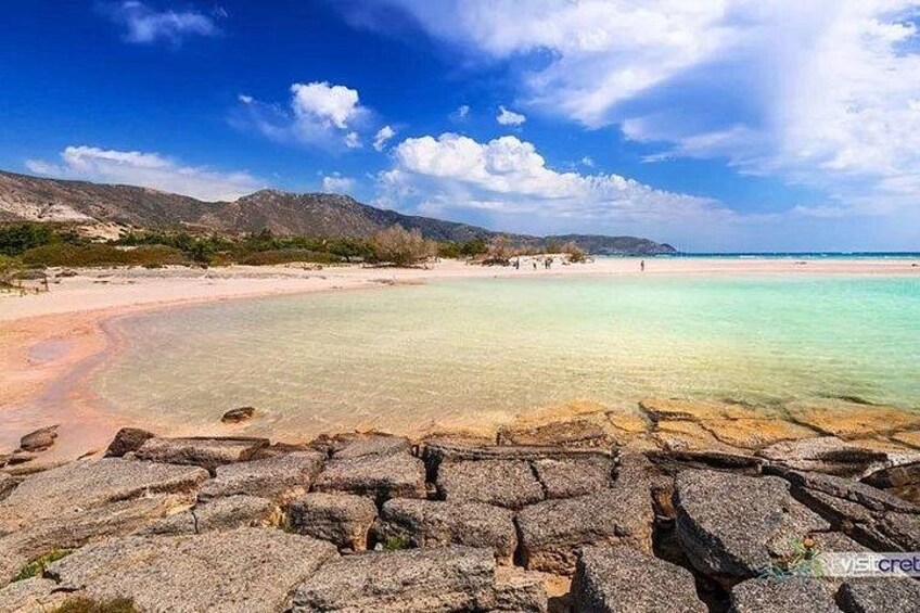 Eine Küstenlandschaft mit klarem türkisblauem Wasser, einem Sandstrand und Felsformationen. 3
