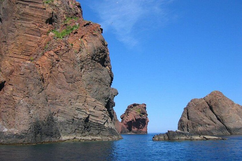 A rocky coastline with layered rock formations and a clear blue sky. 4