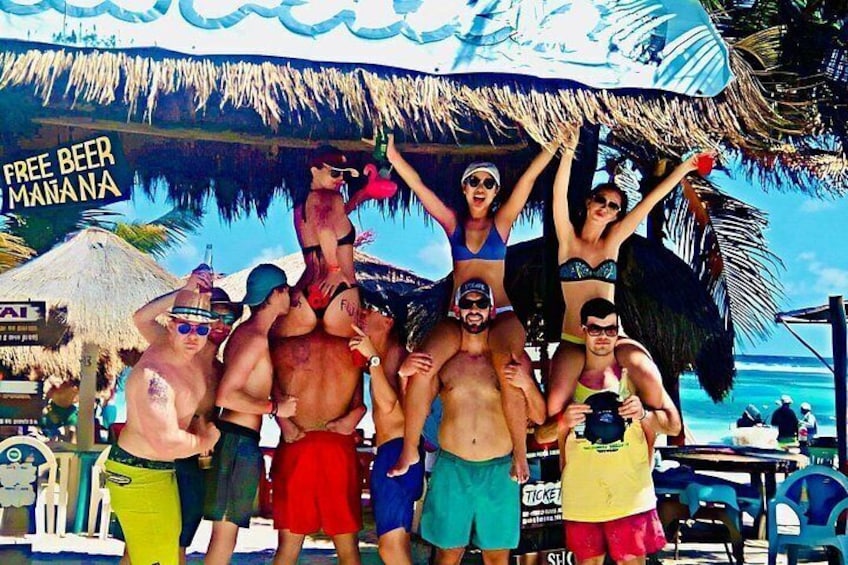 Un grupo de personas en la playa, con un cartel que dice 'CERVEZA GRATIS MAÑANA'. 4