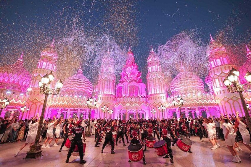A crowd dancing in front of a brightly lit building with domed architecture. 2