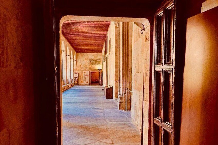 A corridor with a wooden ceiling, stone floor, and a door on the right. 4