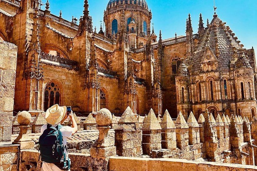 A historic cathedral with intricate architecture, a dome, and a person taking a photo. 1