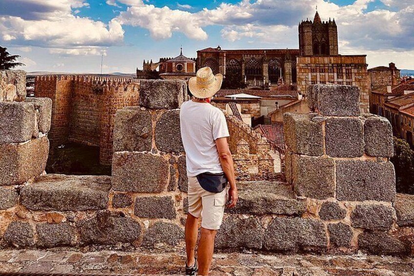 A person standing in front of ancient stone walls with a historic building in the background. 5