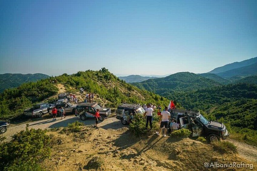A group of people and vehicles on a hillside with a clear view of the surrounding landscape. 3