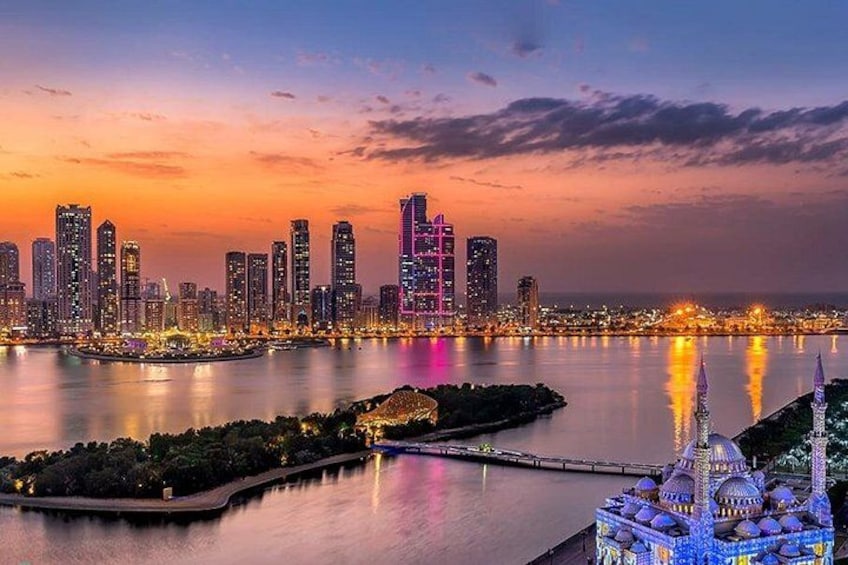 A city skyline at dusk with illuminated buildings, a body of water, and a mosque with blue lights. 3