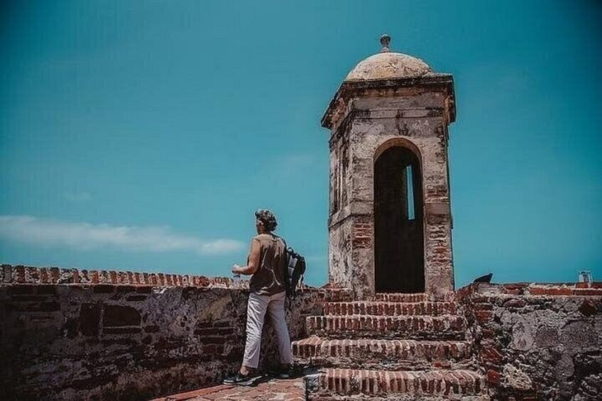 A person standing on a stone wall with a historical building in the background. 2