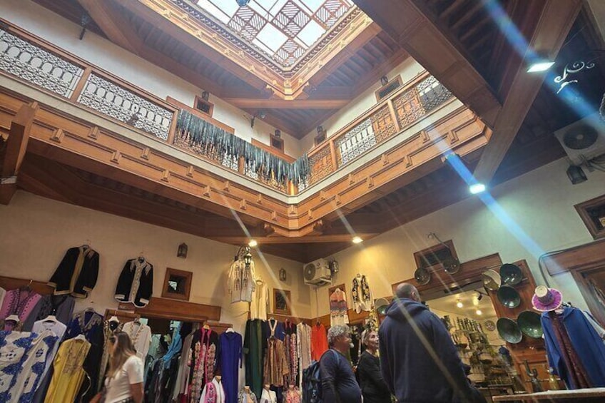 A traditional market with wooden beams, a skylight, and various clothing items on display. 3