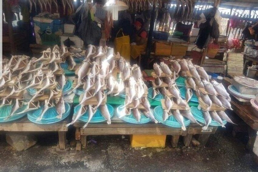 A market stall with fish displayed on blue trays. 4