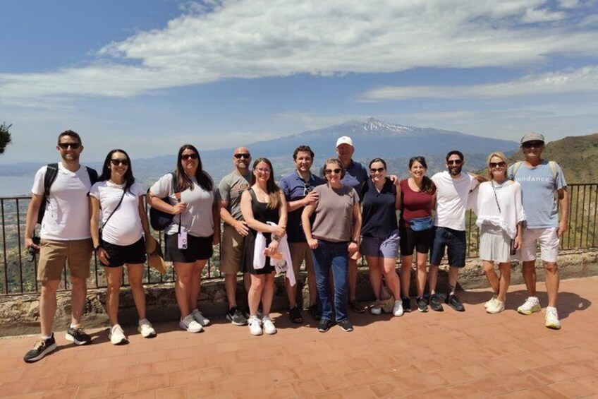 Un grupo de personas de pie en una zona pavimentada, con un paisaje montañoso al fondo. 1