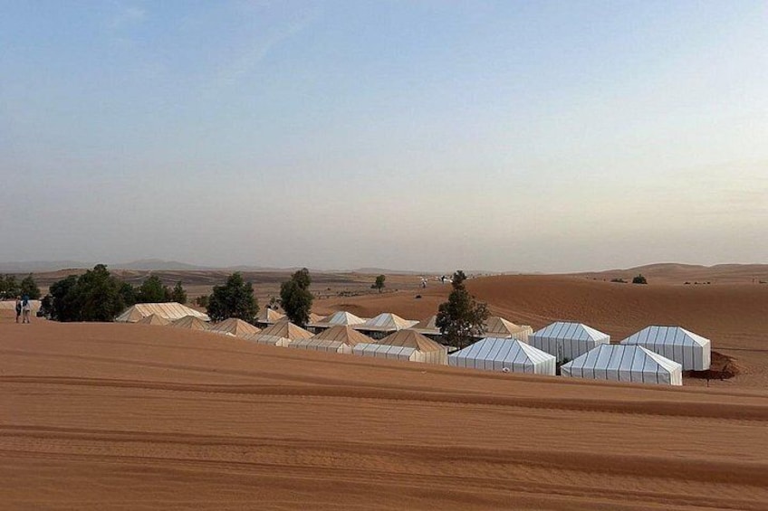 A desert landscape with tents and sparse vegetation. 3