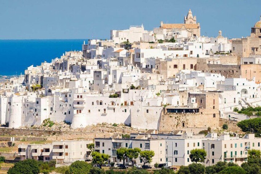 Une ville côtière aux bâtiments blancs, avec une église imposante et une mer d’un bleu limpide. 2